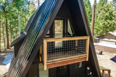 a house with a gambrel roof and a balcony at Modern Black A-Frame overlooking a Meadow w AC! in Shaver Lake