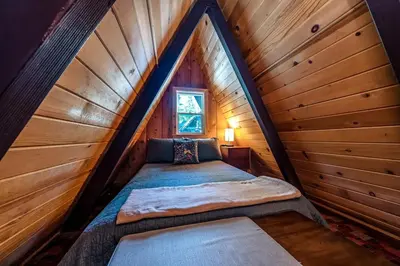 a bed in the attic of a log cabin at A-Frame Escape Unique stay w comfort & style in Shaver Lake