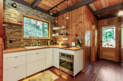 a kitchen with white cabinets and a brick wall at A-Frame Escape Unique stay w comfort & style in Shaver Lake
