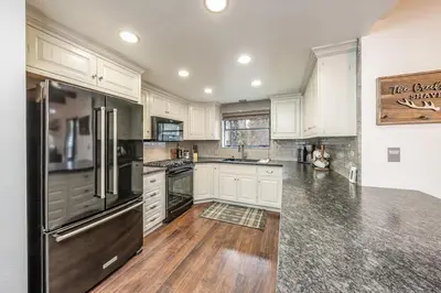 a kitchen with white cabinets and a black refrigerator at Creekside Cabin - Pup-Friendly with AC in Shaver Lake