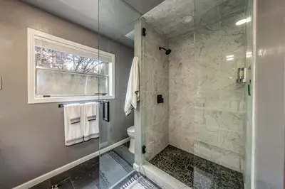 a bathroom with a shower and a toilet and a window at Creekside Cabin - Pup-Friendly with AC in Shaver Lake