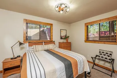 a bedroom with a bed and a chair and windows at The Elderberry Retreat - It's a Dream Location! in Shaver Lake
