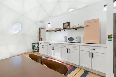 a kitchen with white cabinets and a table at Dome Sweet Dome | Shaver Lake in Shaver Lake