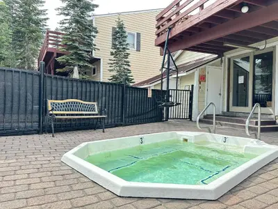 a hot tub on a patio in front of a house at Lakeview Villas #09 condo in Mammoth Lakes