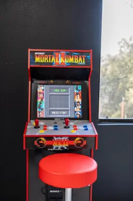 a pinball machine with a red stool in front of it at Secluded Mtn Top Family Haven with Spa, Views & Arcade in Oakhurst