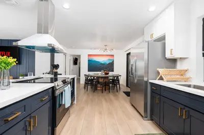 a kitchen with blue cabinets and a dining table at Secluded Mtn Top Family Haven with Spa, Views & Arcade in Oakhurst