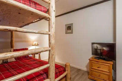a bedroom with two bunk beds and a flat screen tv at Updated 2 Bedroom 2 Bathrooms 1849 Condos #109 Steps to Canyon Lodge Sleeps 6 in Mammoth Lakes