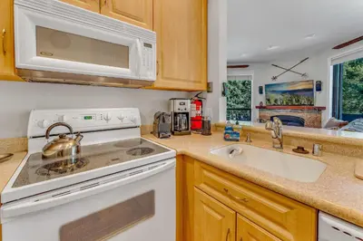 a kitchen with a white stove top oven next to a sink at Palisades Condo - Walk to Ski Lift! in Olympic Valley