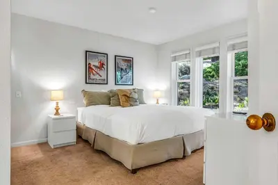 a white bedroom with a large bed and windows at Palisades Condo - Walk to Ski Lift! in Olympic Valley