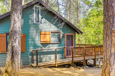 a blue house with a porch in the woods at California Mountain Cabin with Lake Access and Deck! in Long Barn