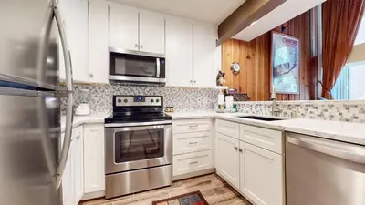 a kitchen with white cabinets and stainless steel appliances at Mammoth Ski & Racquet Club #118 condo in Mammoth Lakes
