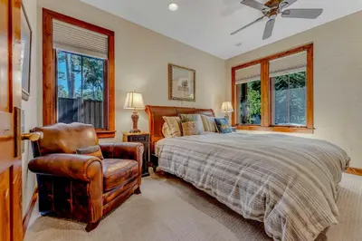 a bedroom with a bed and a chair and windows at Lakefront Retreat Across from Homewood Resort in Homewood