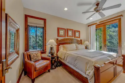 a bedroom with a bed and a chair and windows at Lakefront Retreat Across from Homewood Resort in Homewood