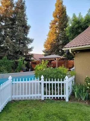 a white fence in front of a yard with a pool at 3 Bedrooms,Beautiful House with Hot Tub, Pool Oasis and Fire Pit in Clovis