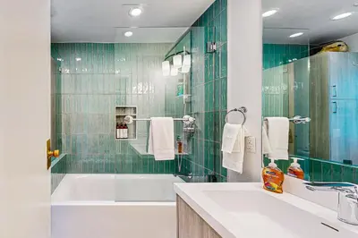 a bathroom with a tub and a sink and green tiles at Modern Mountain Getaway in Olympic Valley