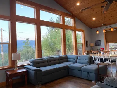 a living room with a blue couch in a room with windows at The Hilltop Cabin Retreat in Bass Lake Heights in Oakhurst