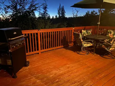 a wooden deck with a table and a grill and an umbrella at The Hilltop Cabin Retreat in Bass Lake Heights in Oakhurst