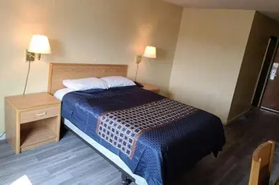 a hotel room with a bed and a night stand at MetroParc 'nSuites in Stockton