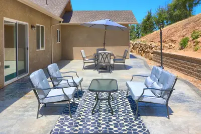 a group of chairs and an umbrella on a patio at Yosemite Hilltop Gated Villa near Oakhurst, Bass Lake and Mariposa w EVCharger Hottub Grill and Awesome Views! in Ahwahnee