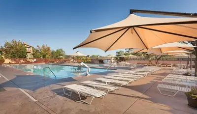 a group of chairs and an umbrella next to a pool at WorldMark Angels Camp - 2BD in Angels Camp