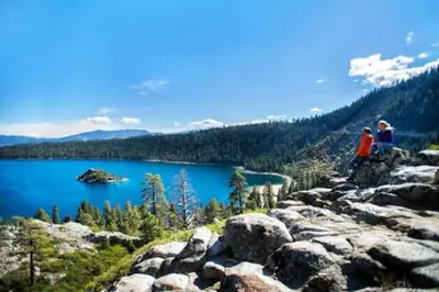 two people sitting on top of a mountain overlooking a lake at Marriott Grand Residences Luxury 1BD in South Lake Tahoe