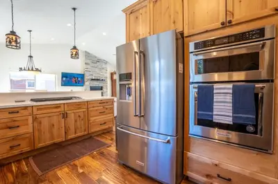 a kitchen with stainless steel appliances and wooden cabinets at CHALET LU - Modern Luxury 4 bed 2.5 bath Chalet by Lake Baron in South Lake Tahoe in South Lake Tahoe