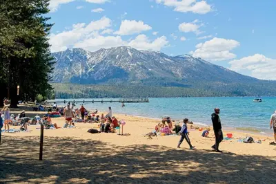 a group of people on a beach with mountains in the background at CHALET LU - Modern Luxury 4 bed 2.5 bath Chalet by Lake Baron in South Lake Tahoe in South Lake Tahoe