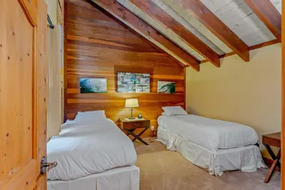 two beds in a room with wooden walls at Alpine Meadows Retreat 3 Min to Base with Hot Tub in Alpine Meadows