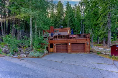 a house with a large garage in the woods at Alpine Meadows Retreat 3 Min to Base with Hot Tub in Alpine Meadows