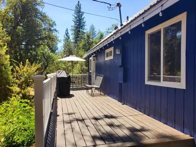 a blue house with a wooden deck with an umbrella at -Serendipity Lodge at Yosemite- BBQ-Full Kitchen-King Bed in Oakhurst