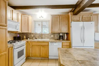 a kitchen with wooden cabinets and a white refrigerator at The Valley View- Pine Mountain Lake Cabin home in Groveland