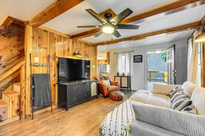 a living room with wooden walls and a ceiling fan at Hike, Ski and Fish Charming Cabin in Twain Harte! in Twain Harte
