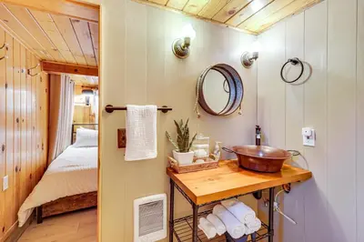 a bathroom with a sink and a bed in a room at Peaceful Wooden Cabin, 2 Mi to Bass Lake! in Oakhurst