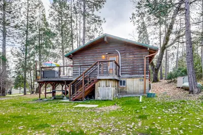 a cabin in the woods with a large deck at Peaceful Wooden Cabin, 2 Mi to Bass Lake! in Oakhurst