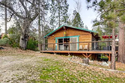 a cabin in the woods with a large deck at Peaceful Wooden Cabin, 2 Mi to Bass Lake! in Oakhurst