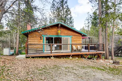 a log cabin in the woods with a deck at Peaceful Wooden Cabin, 2 Mi to Bass Lake! in Oakhurst
