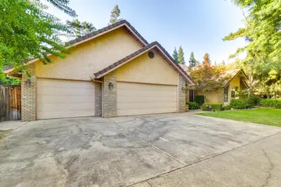 a house with two garage doors in a driveway at 1 Mi to Applegate Park Zoo Pet-Friendly Home in Merced