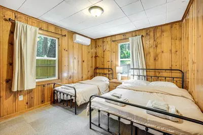 two beds in a room with wooden walls at Walk to Winery Cozy Cabin with Fire Pit in Murphys in Murphys