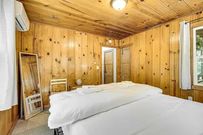 a bedroom with a white bed in a wooden wall at Walk to Winery Cozy Cabin with Fire Pit in Murphys in Murphys