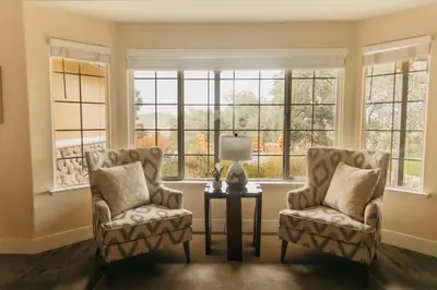 two chairs and a table in a room with windows at Panoramic Lookout Sierra Serenity BBQ by CasaOso in Mariposa