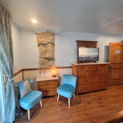 a room with two chairs and a dresser and a television at Kings River Reflections in Sanger