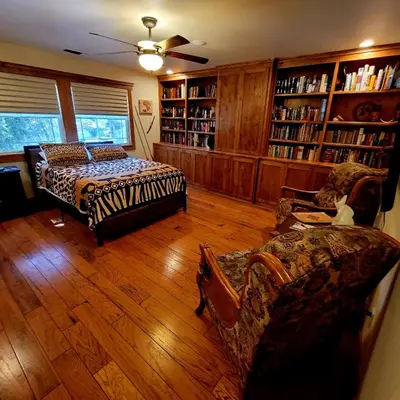 a living room with a couch and chairs and bookshelves at Kings River Reflections in Sanger