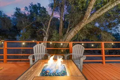 a fire pit on a deck with two chairs at HIlltop Oasis with games, hot tub, Fire-pit, Deck, Views in Oakhurst