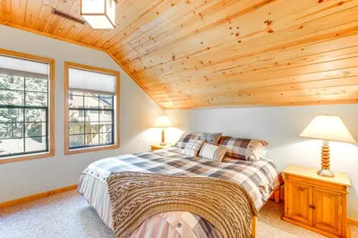 a bedroom with a large bed and two windows at Deck with Mountain Views Cabin in Bear Valley! in Bear Valley