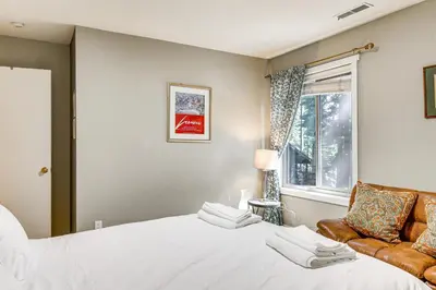 a bedroom with a bed and a chair and a window at Forest-View Haven with Game Room Tahoe City Gem! in Tahoe City