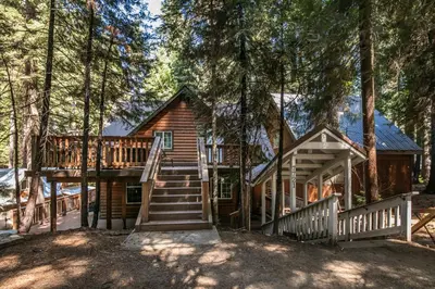 a cabin in the woods with stairs leading up to it at Cabin minutes from Yosemite in Fish Camp