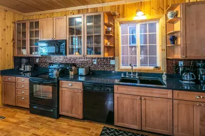 a kitchen with wooden cabinets and black appliances at Cabin minutes from Yosemite in Fish Camp