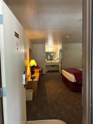 a hotel room with a bed and a desk with a lamp at Mi Wuk Village Inn in Mi-Wuk Village