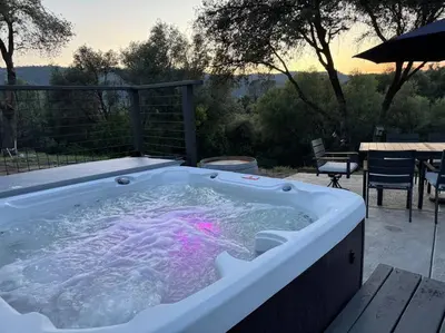 a hot tub on a patio with a table and chairs at Manzanita Hideaway Hot Tub Sunset views Yosemite in Ahwahnee