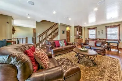 a living room with leather furniture and a staircase at Lv12 luxury villa with hot tub, close to skiing in Glenbrook